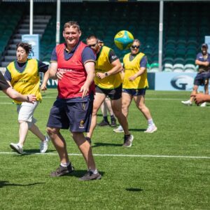 Shot of the group on the pitch in coloured bibs having a go at the game