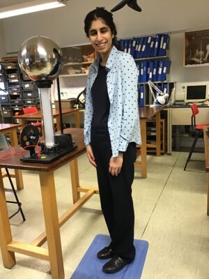Female student stood on a plastic tray in front of the Van de Graaff generator