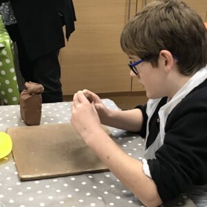 Male student playing with a piece of brown clay