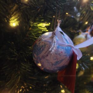 A white and blue marbled bauble, with speckles of red.