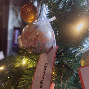 A bauble by George that is orange, white, blue and red