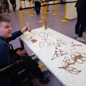 Student using melted chocolate to create designs on a table