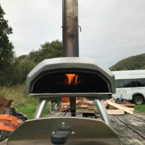 Pizza stove with fire burning inside, NCW minibus in the background