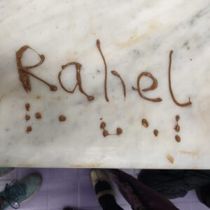 The name 'Rahel' written in melted chocolate, with the same name in Braille underneath