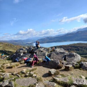 Group of male and female students on top of a scenic Welsh mountain on a bright, sunny day