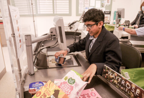 Female student at the checkout scanning customer items