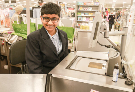 Female student smiling at the camera sat at the checkout