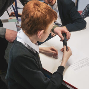Male student is testing out the Orcan Read. A pen shaped device which takes a photo of text and reads it back