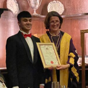 Mustafa is presented with an award from Master Margaret Fitzsimons, for his commitment as Head Student for 2021/22