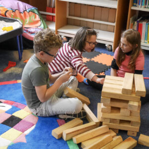Three children are playing with the giant jenga