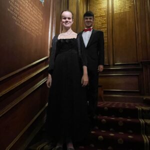 Martha and Mustafa are posing for a photo in their fancy clothes on the stairs at the Tallow Chandlers Hall