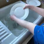 Student is washing up plates in the sink