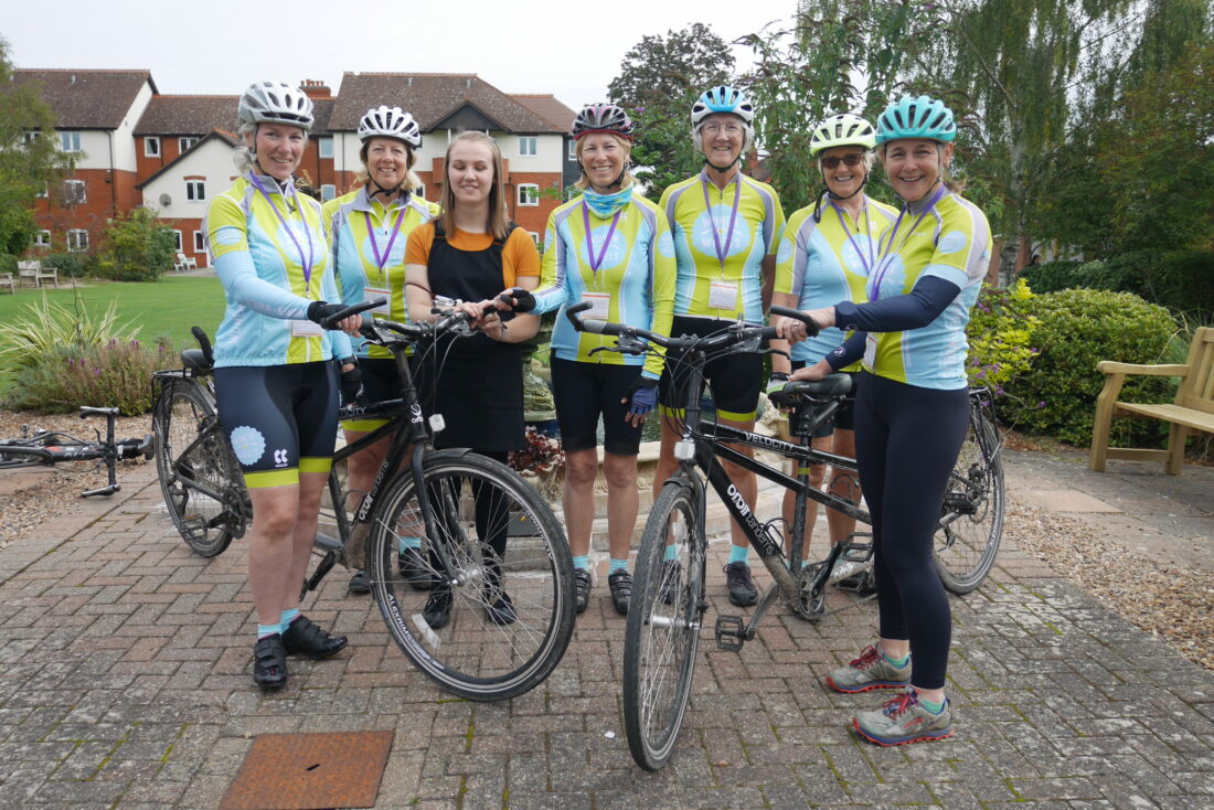 image of six WOW members holding x2 NCW tandem bikes. NCW student Lydia is stood in the centre of the group. They are all smiling at the camera.