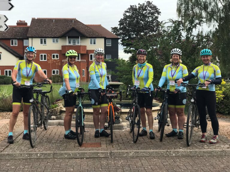 image of 6 members of WOW holding theirs bikes, smiling at the camera. They are stood in front of the fountain at NCW.