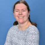 Student Emma - image is head and shoulders shot with a blue background. Emma is smiling