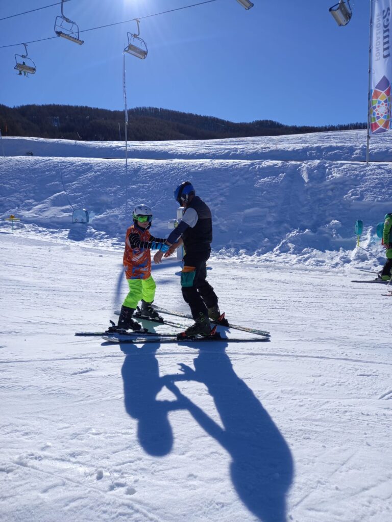 Instructor and student on the slops, facing each other and holding on.