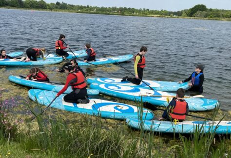 image of students on the lake paddle boarding