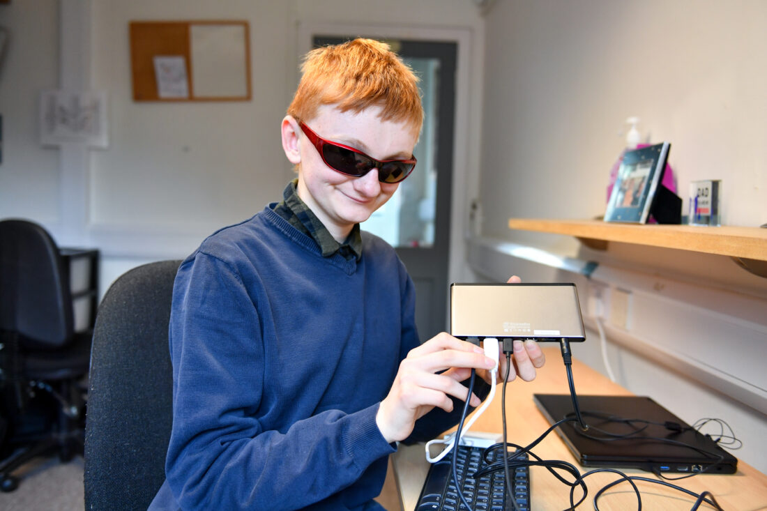 image of a student in an access technology lesson showing IT equipment and smiling