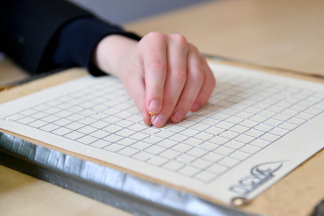 image of a hand feeling a raised grid