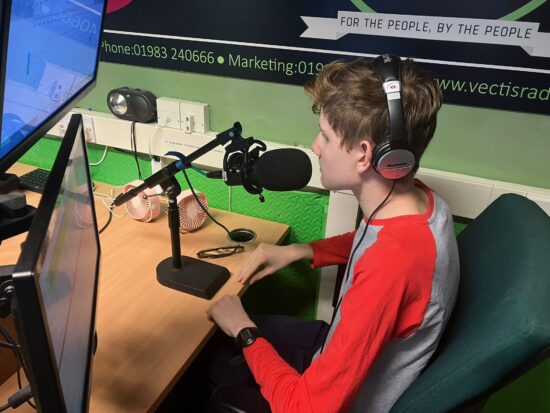 image of Leo on the radio wearing headphone and talking into the microphone