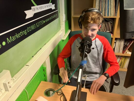 image of Leo on the radio wearing headphone and talking into the microphone