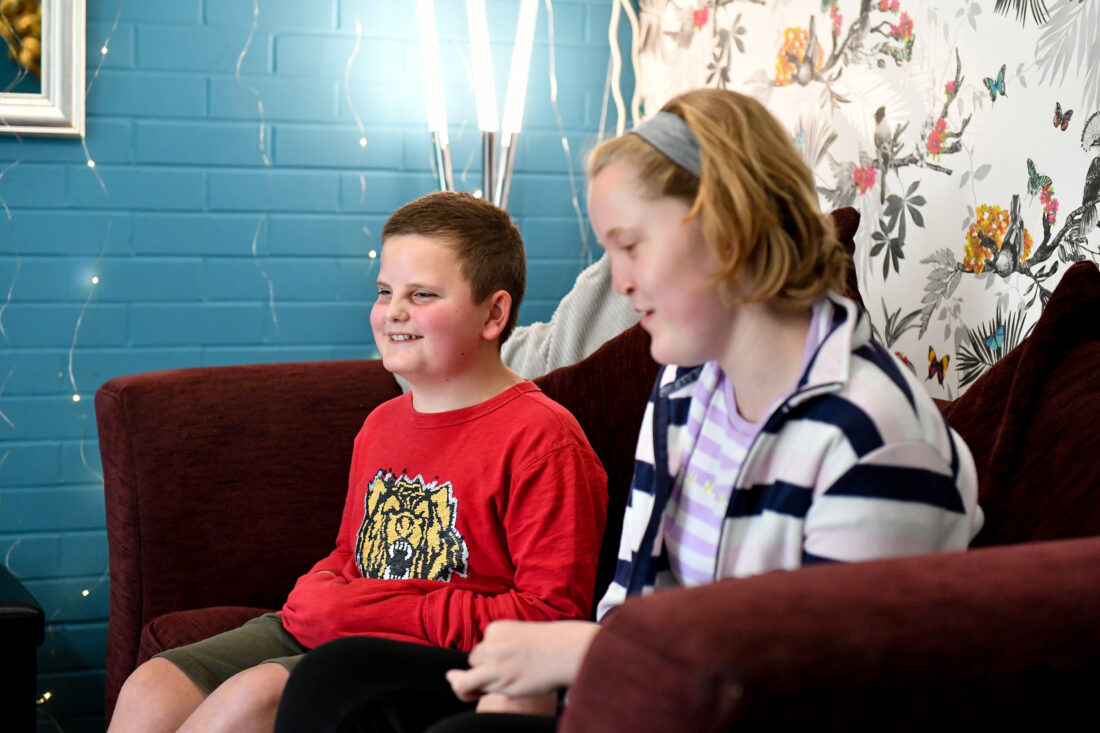 image of two students sat on a sofa smiling. They are in a Lower School House