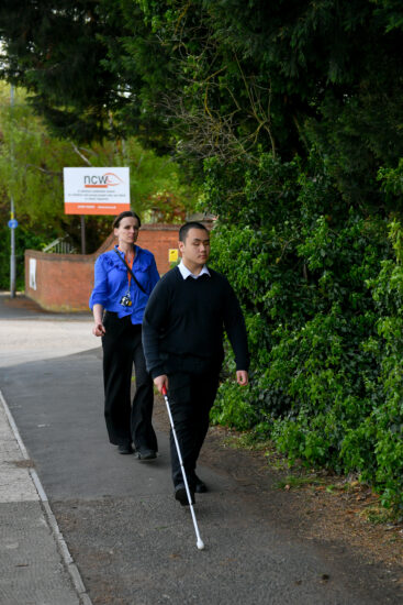 image of a student walking with a cane during a mobility session 