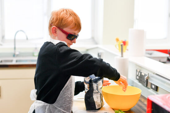 image of a student during an ILS adding ingredients to a yellow plastic bowl 