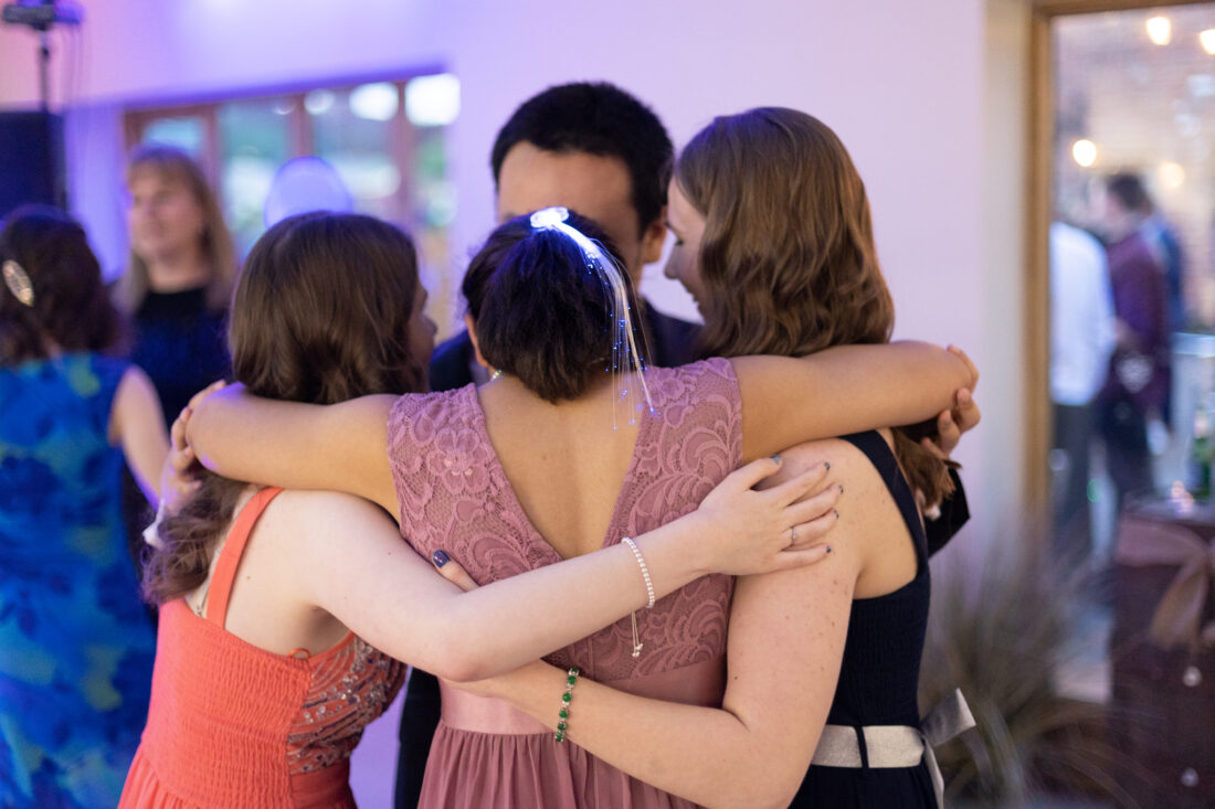 image of four students hugging and dancing