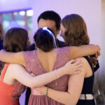 image of four students hugging and dancing