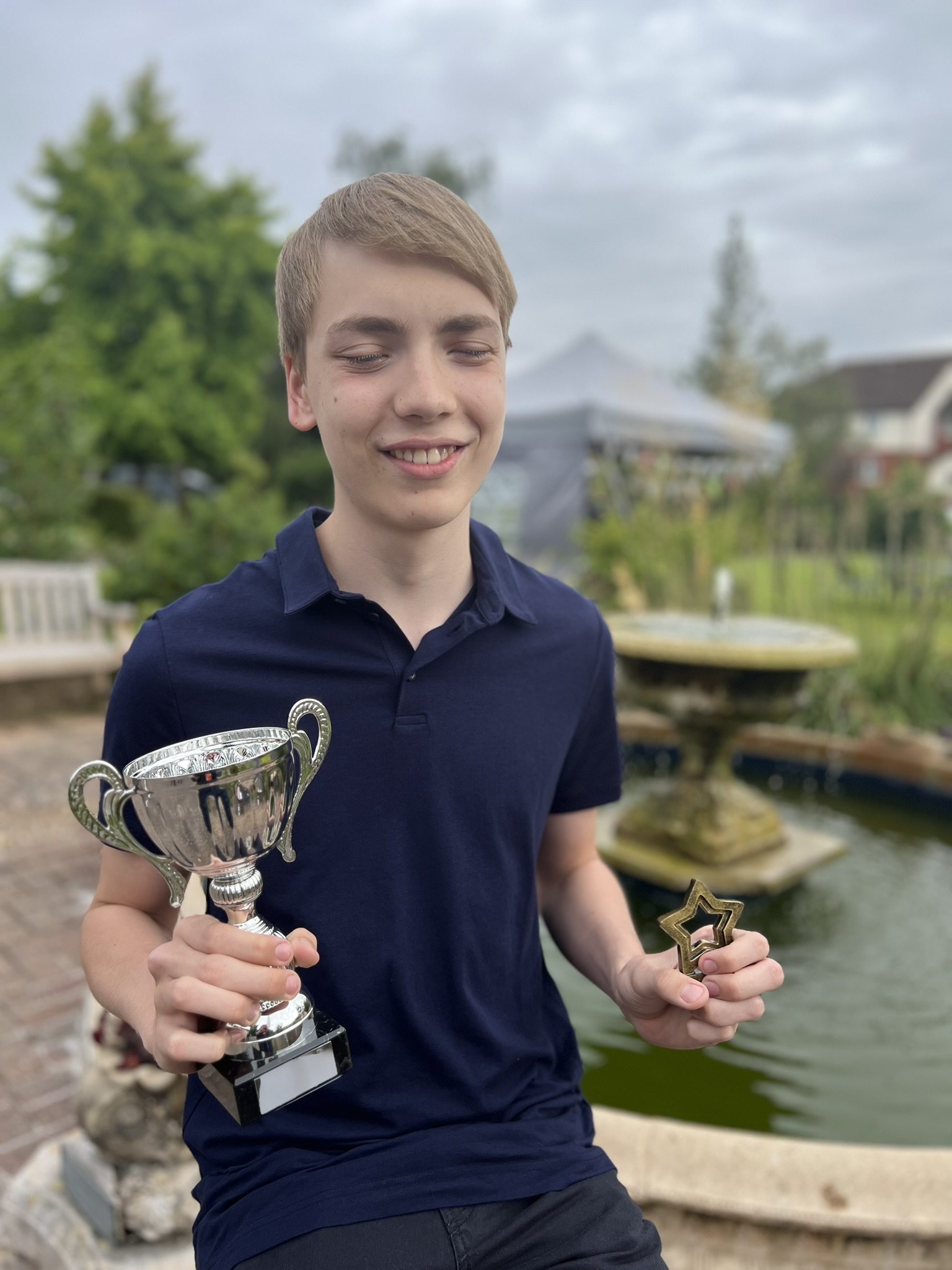 IMage of Erik sat by the fountain at NCW holding his trophies smiling