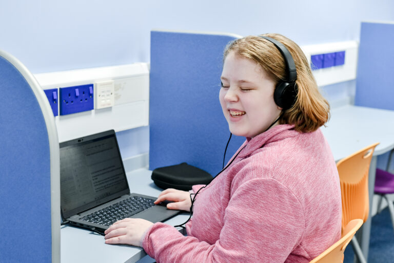 Photo of student smiling working on a laptop