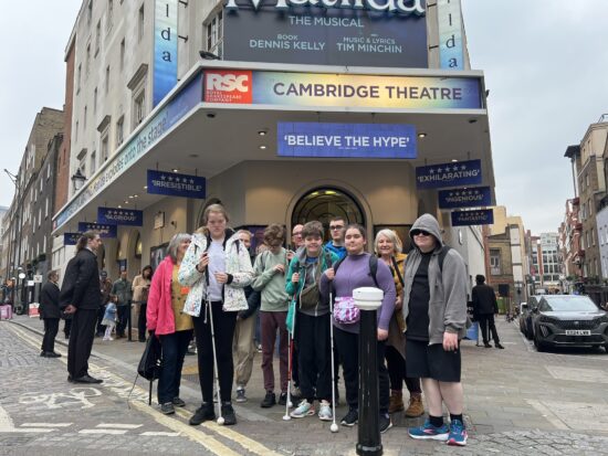 group photo of students and staff stood outside the theatre smiling
