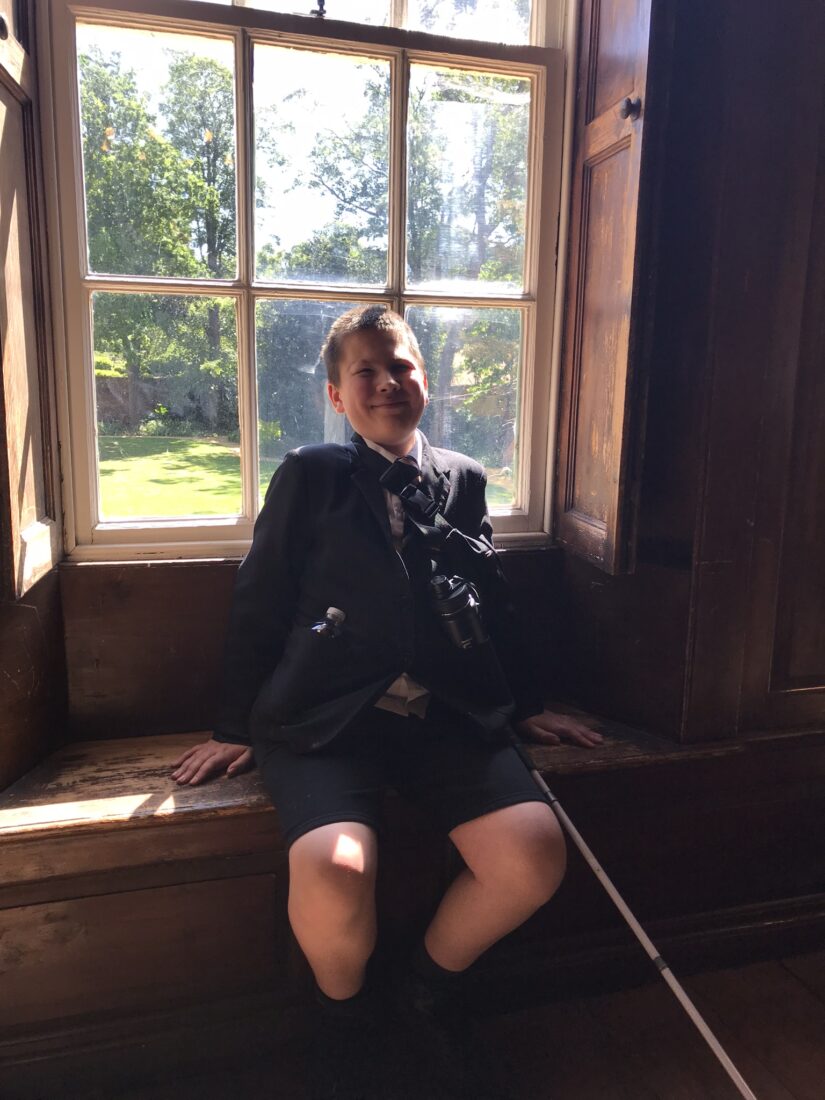 Photo of Ed smiling whist sat on a wooden window seat