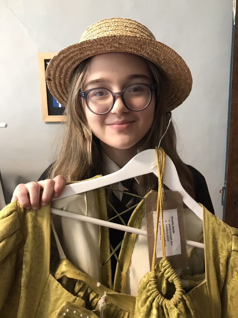 Photo of Bella trying on a vintage hat and holding a yellow dress