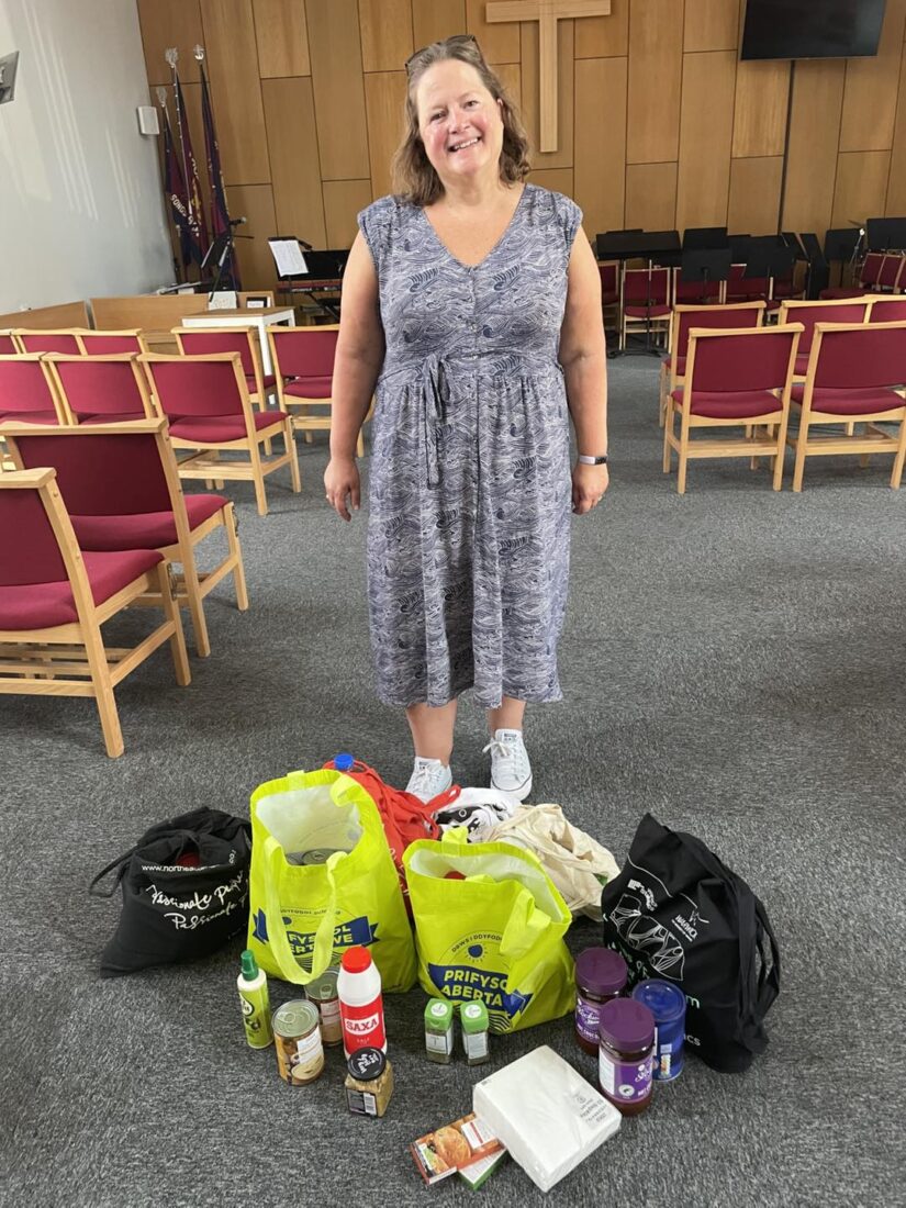 Photo of Mrs Rossoman smiling at the camera whilst donating the food