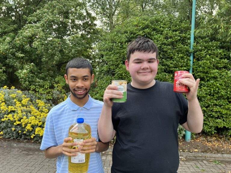 Photo of two students smiling whilst holding dry goods in their hands