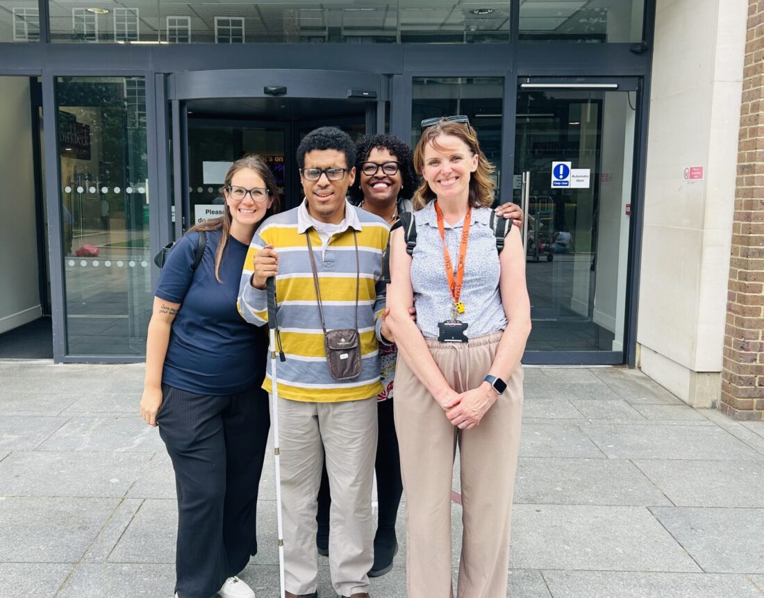 Photo of Sarah from Guide Dogs, Alejandro, Katie from NCW and Gigi Alejandro's mum stood smiling for a group photo outside of the university building