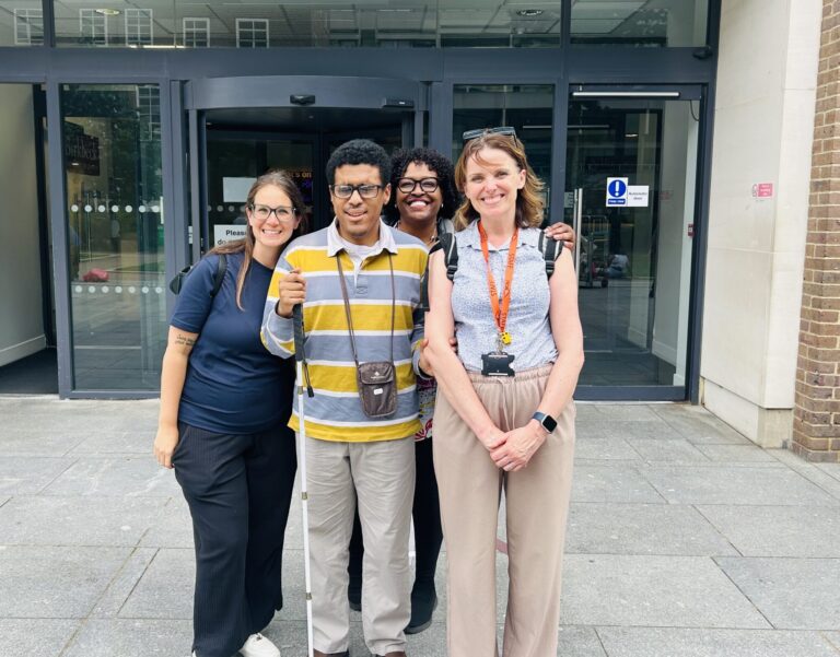 Photo of Sarah from Guide Dogs, Alejandro, Katie from NCW and Gigi Alejandro's mum stood smiling for a group photo outside of the university building