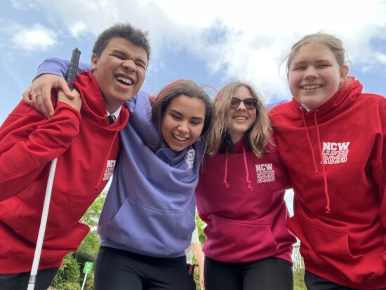 four student smiling whist wearing bright leavers hoodies