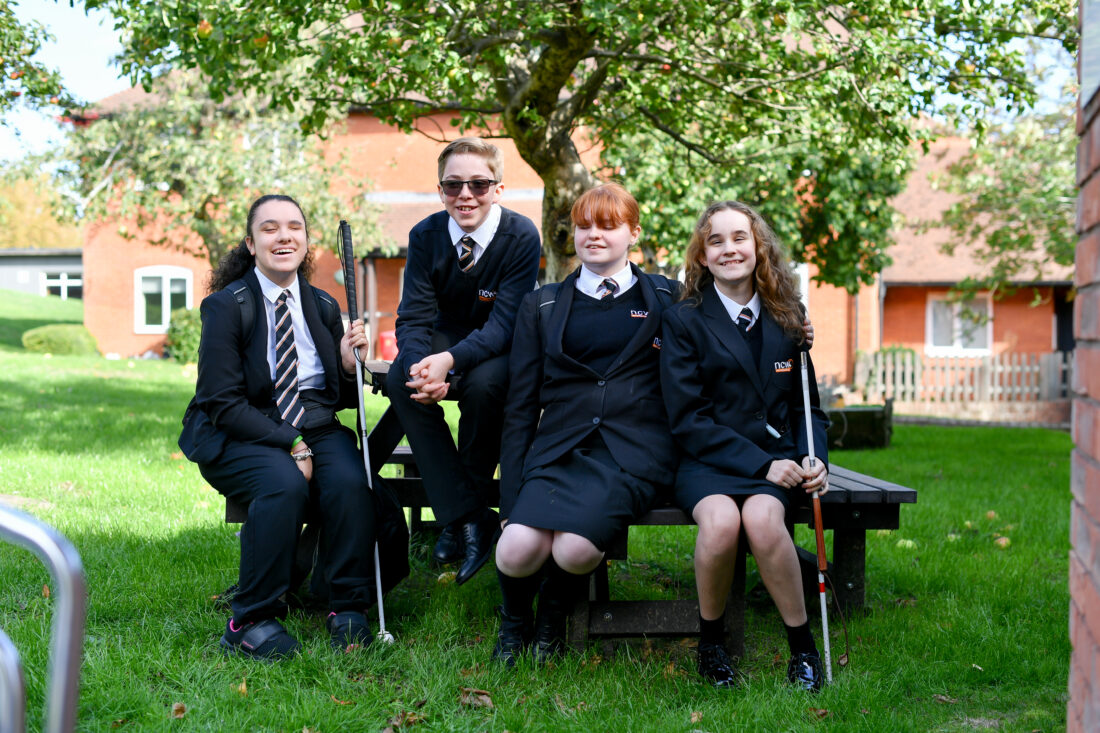 Photo of four students sat around a picnic bench chatting