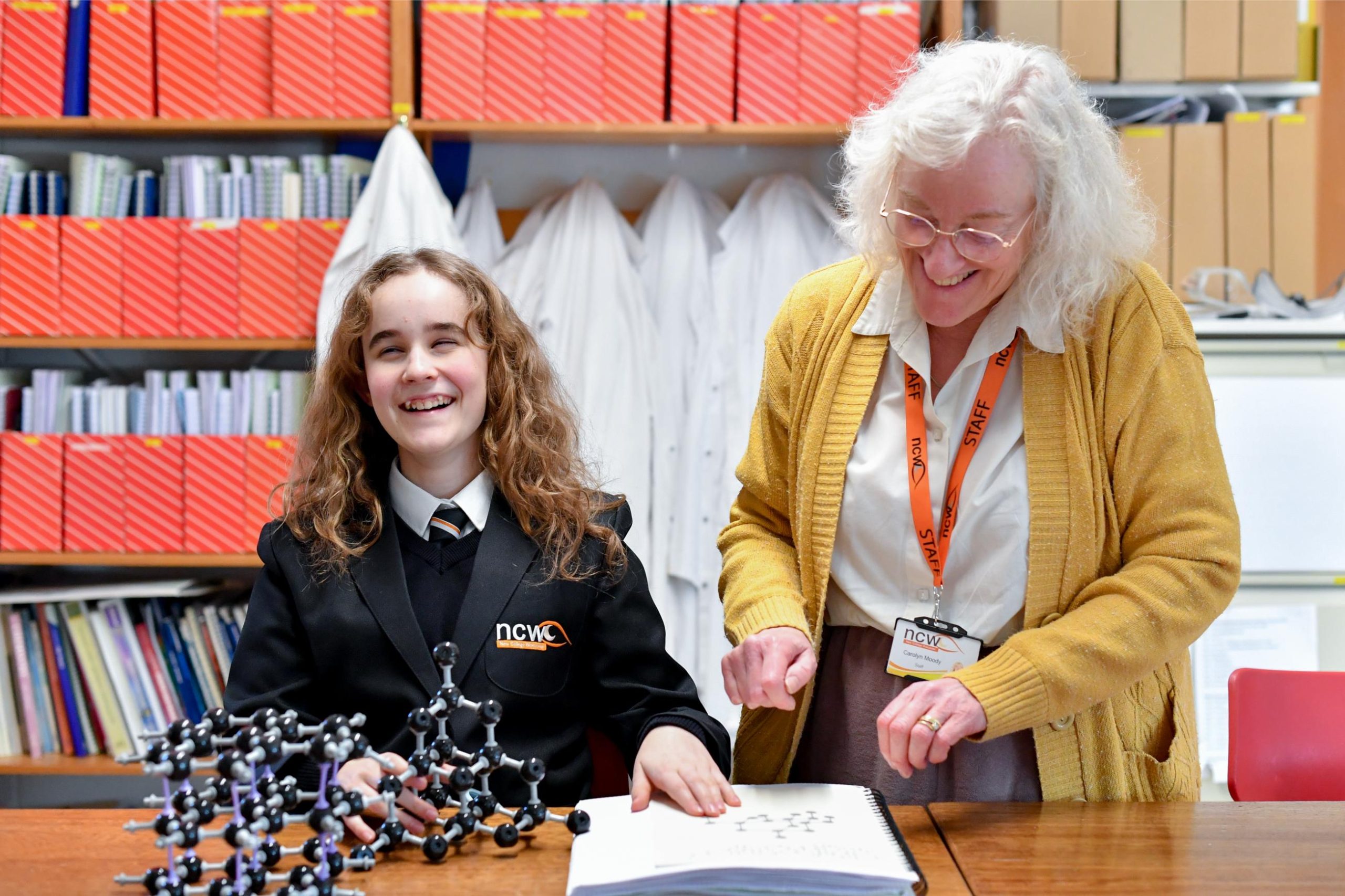 photo of a student reading braille in a science lessons and laughing with the teacher