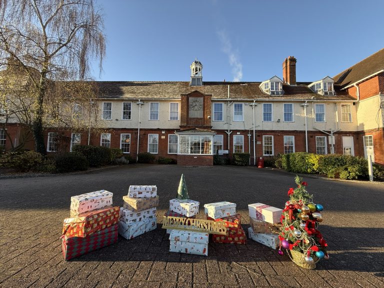 shoe boxes stacked up outside the school building with an xmas tree and merry christmas sign