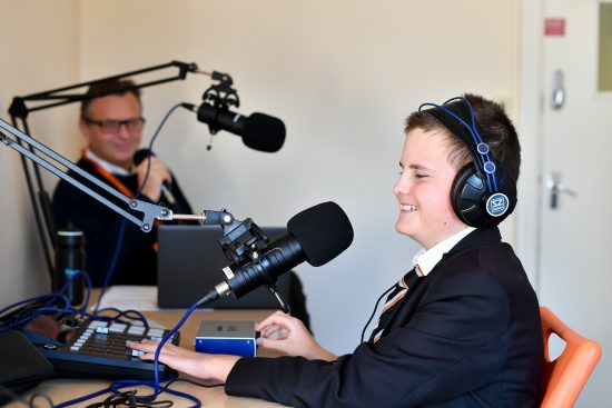 NCW student Lawson is sitting at a radio desk smiling