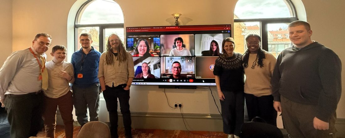 students, NCW staff and Ecrubox staff posing for a photo in front of a large screen