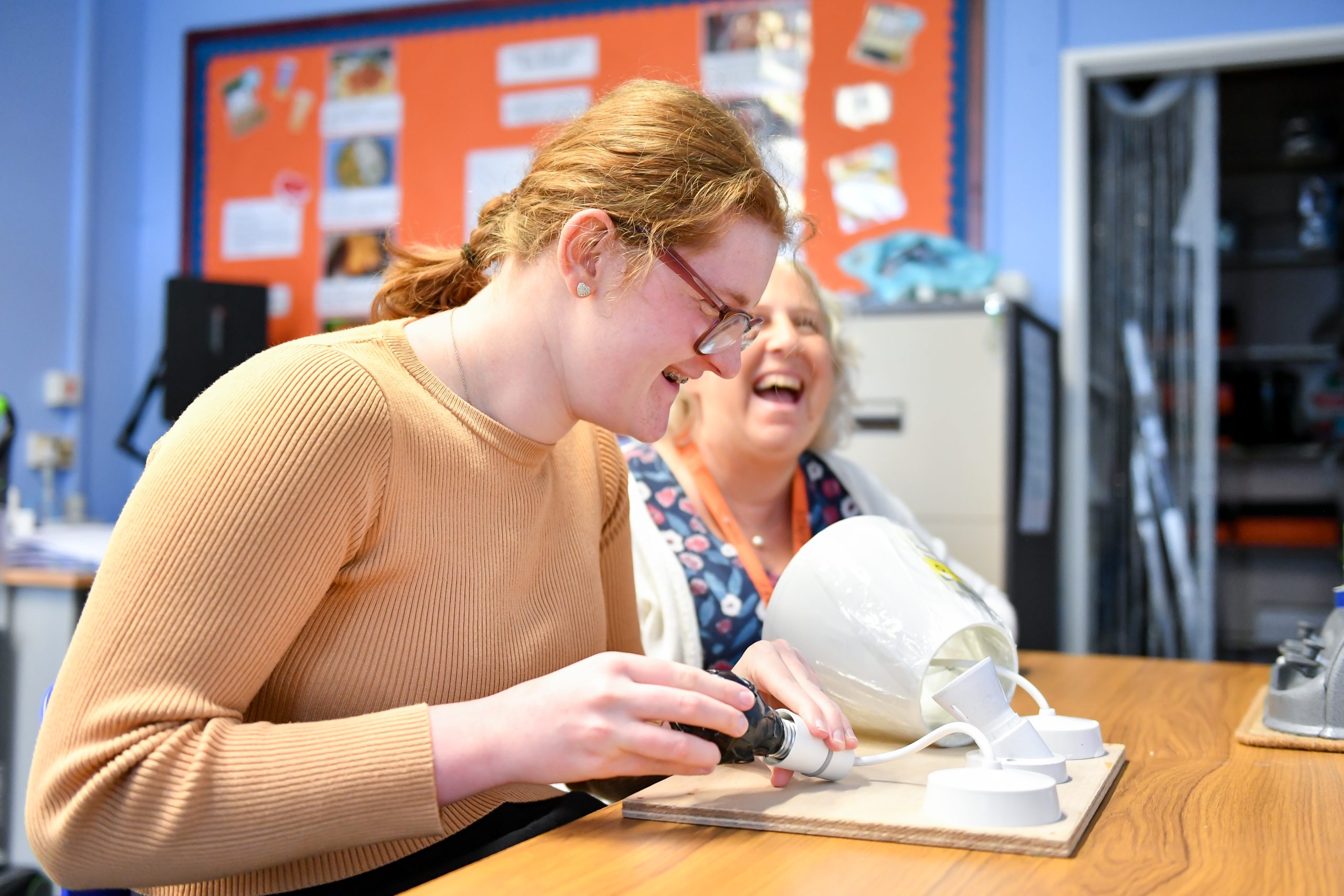A student learning to change a light bulb with Emma Williams