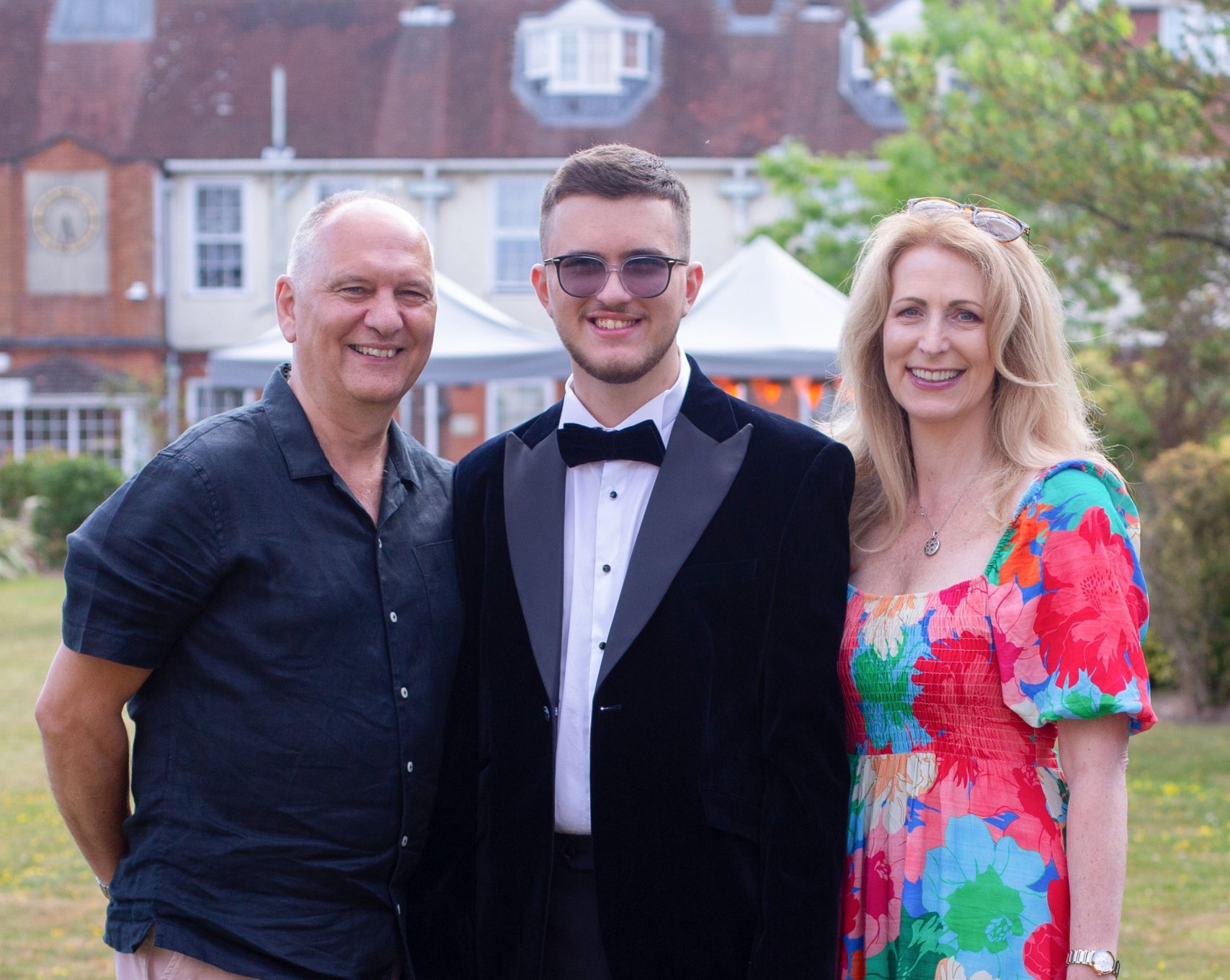 photo of a student at prom with their parents smiling