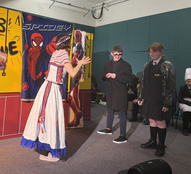 two students on the stage with an actor smiling