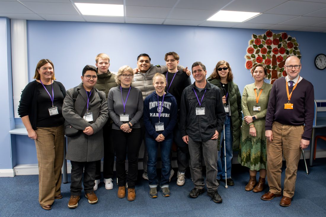 group photo of students and staff smiling at the camera whilst in the LRC at NCW