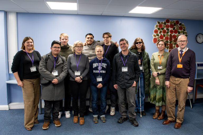 group photo of students and staff smiling at the camera whilst in the LRC at NCW